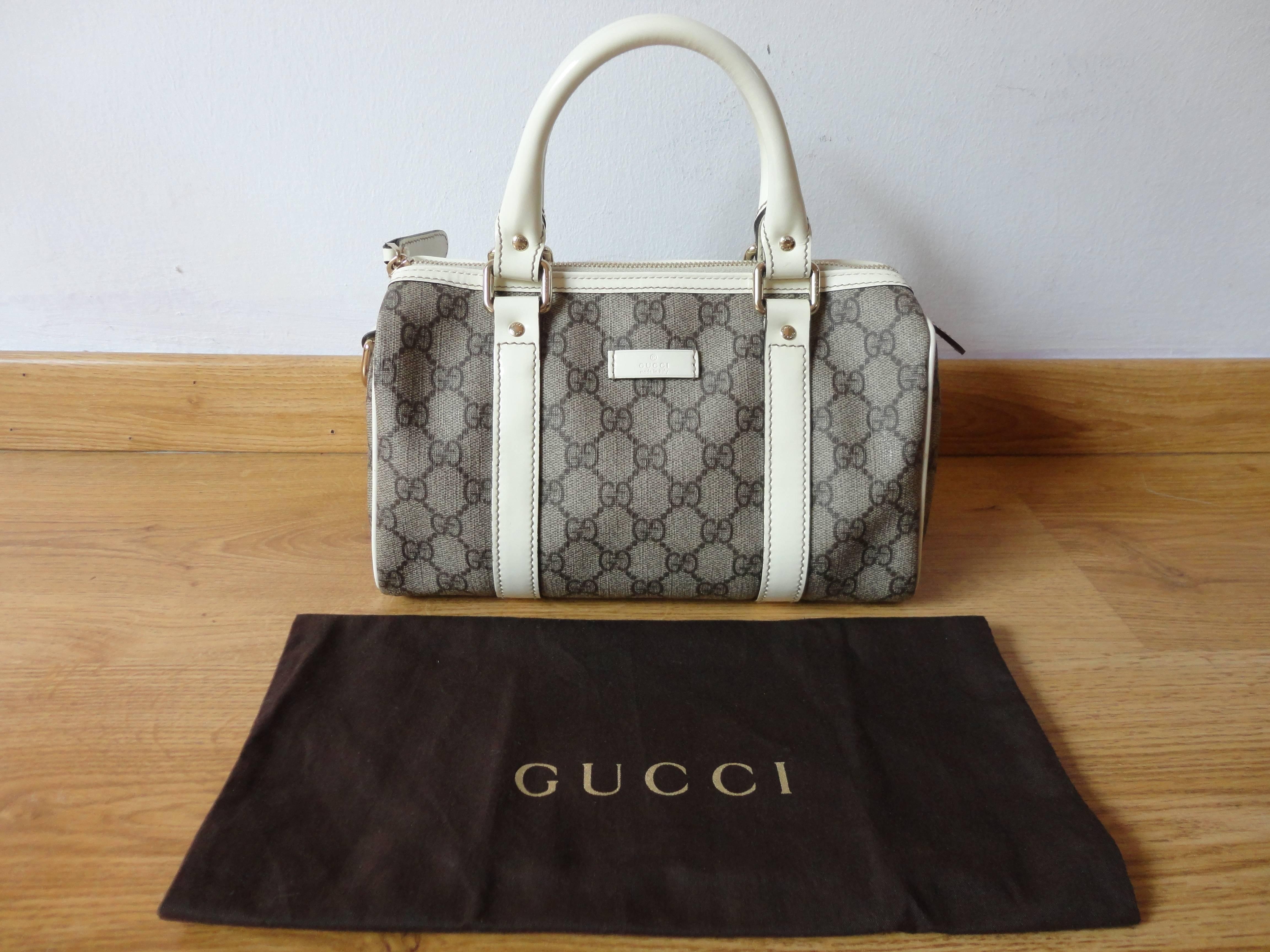 Amazing GUCCI GG Monogram Small Joy Boston. The bag features white cowhide leather trim and rolled top handles with polished gold hardware. The top zipper opens to a dark brown fabric interior with a pocket.
MINT condition, as it was never