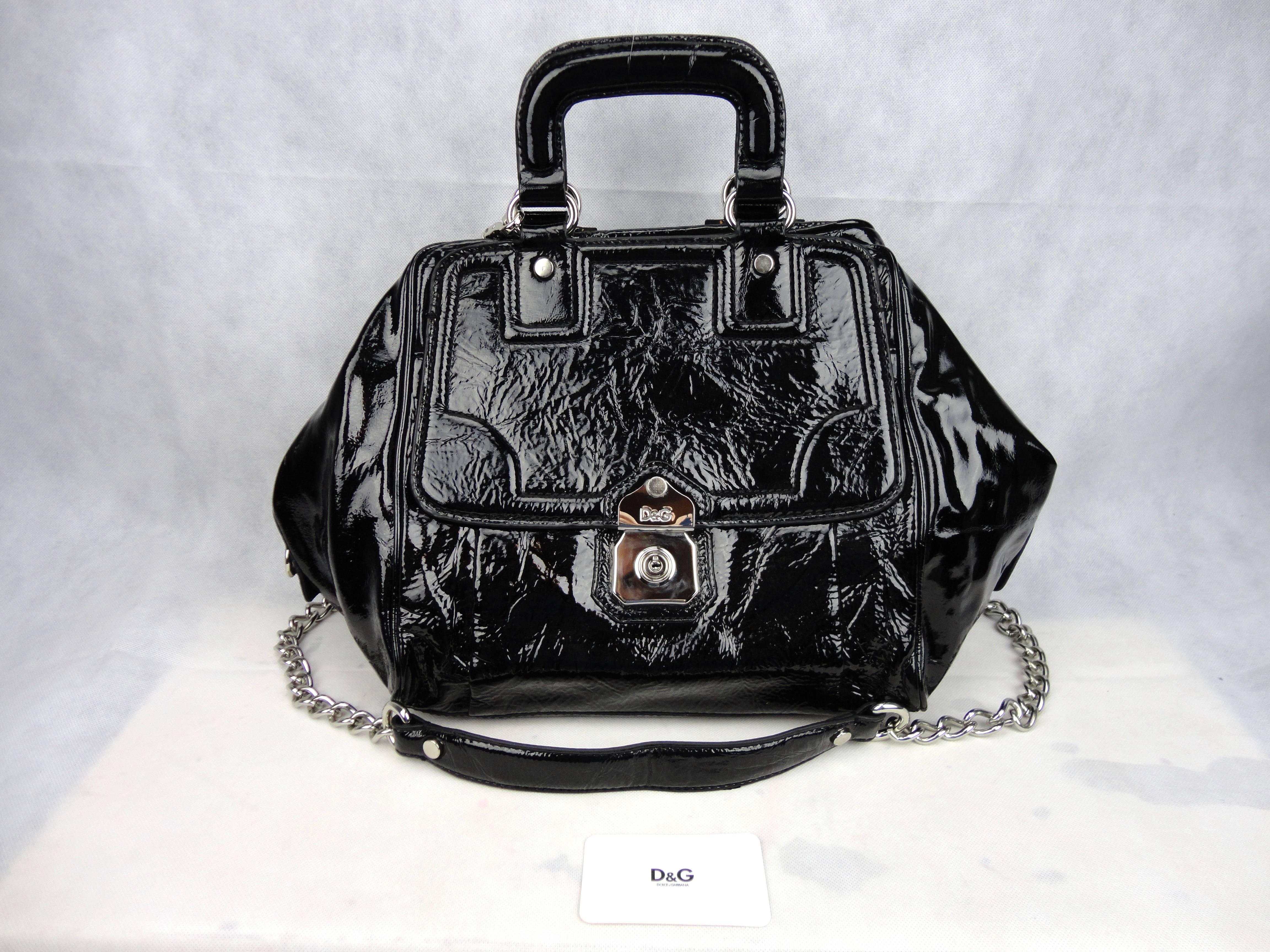 Beautiful black patent leather large Dolce & Gabbana handbag. This bag was hardly carried around and is in great condition, the inside fabric is clean an has one zip pocket. Front flap pocket and small mirror hanging, removable shoulder strap that