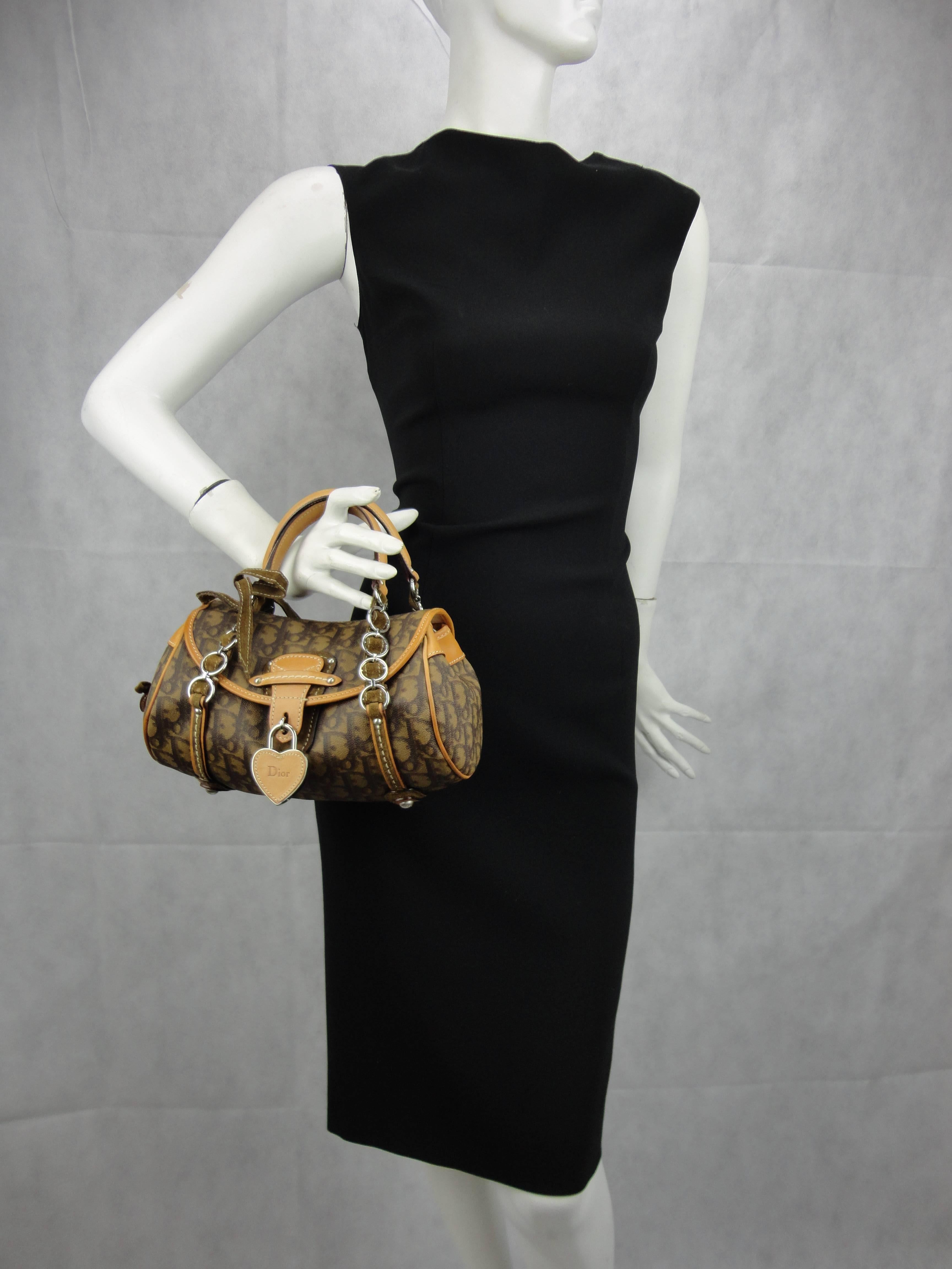 CHRISTIAN DIOR Monogram Romantique Trotter Flap Bag Brown.
This is a lovely compact tote from Christian Dior that is beautifully crafted of Dior monogram canvas. The bag features a short silver chain top handle threaded with suede, a frontal suede