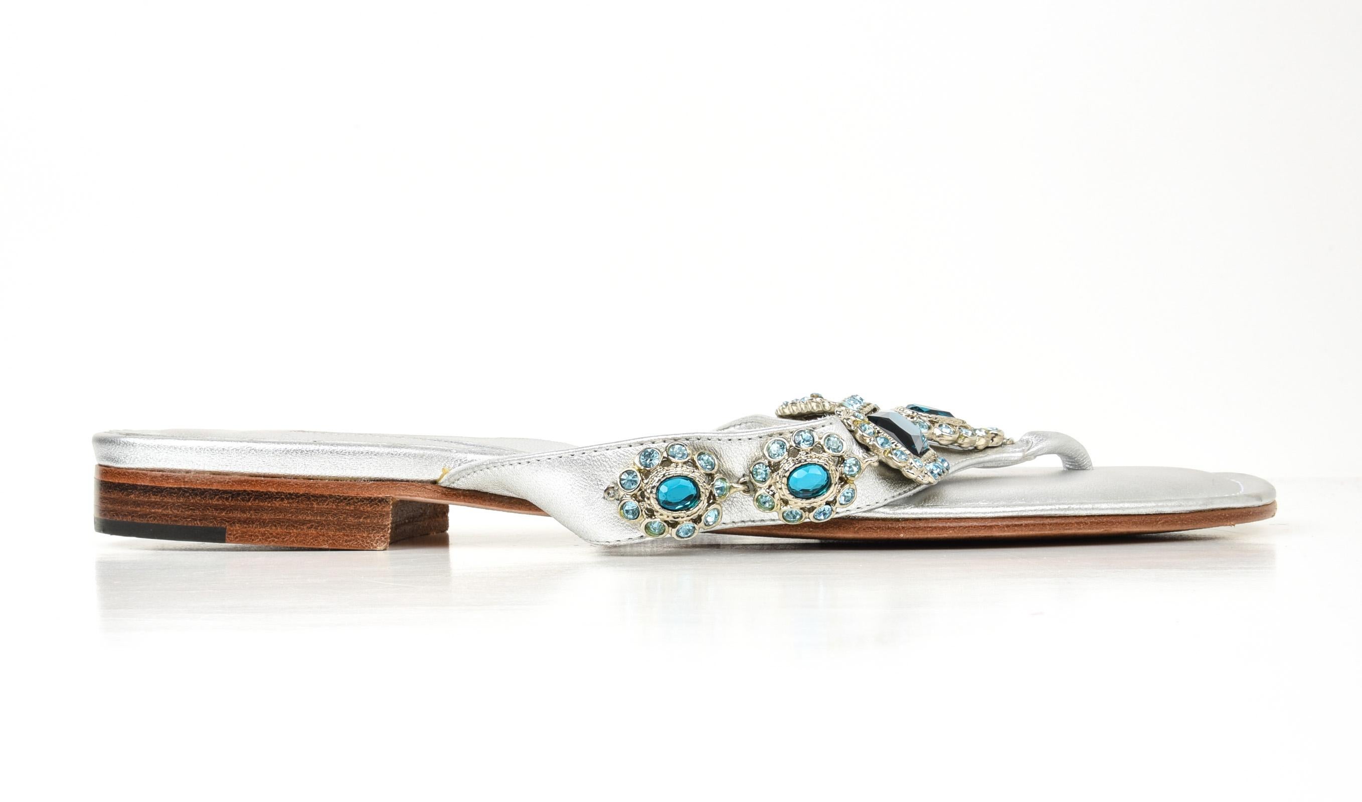 Guaranteed  authentic Manolo Blahnik silver leather thong flat sandal. 
Perfect summer sandal with aqua diamantes across strap.
Comes with sleeper.
  
SIZE  40
USA SIZE  10  
    
SHOE  MEASURES:
HEEL .75