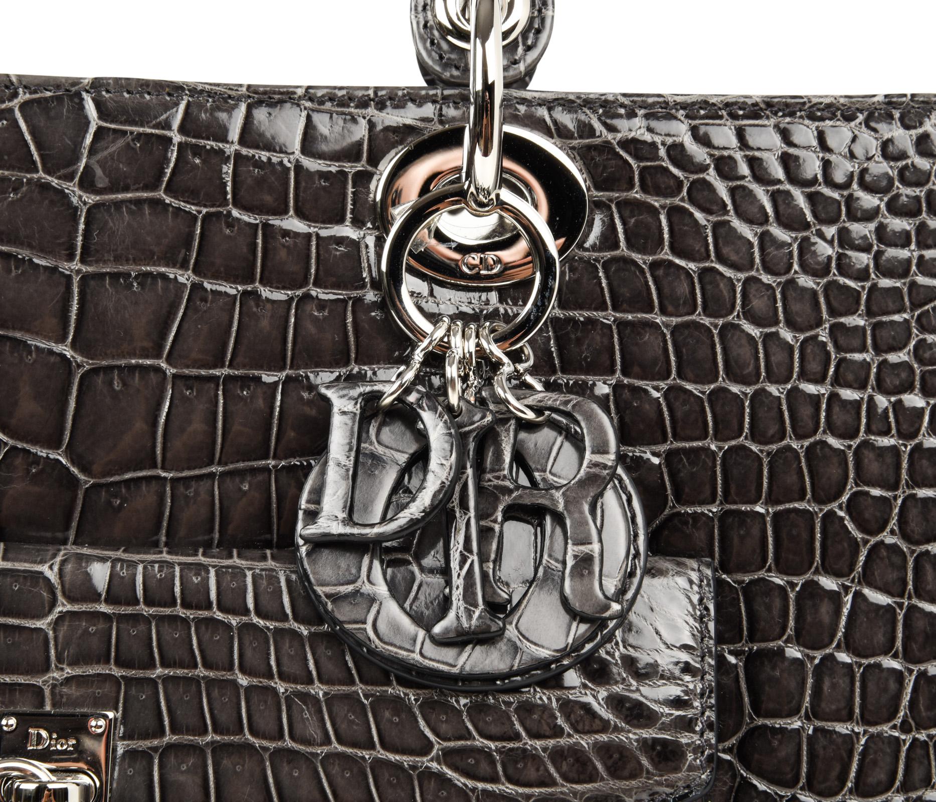 Guaranteed authentic Christian Dior Lady Dior Front Pocket Gray crocodile limited edition bag with silver toned hardware.
Crafted by hand this is the flagship model.
Signature logo charms.
Top zipper closure with signature toggle.  
Zipper pocket on