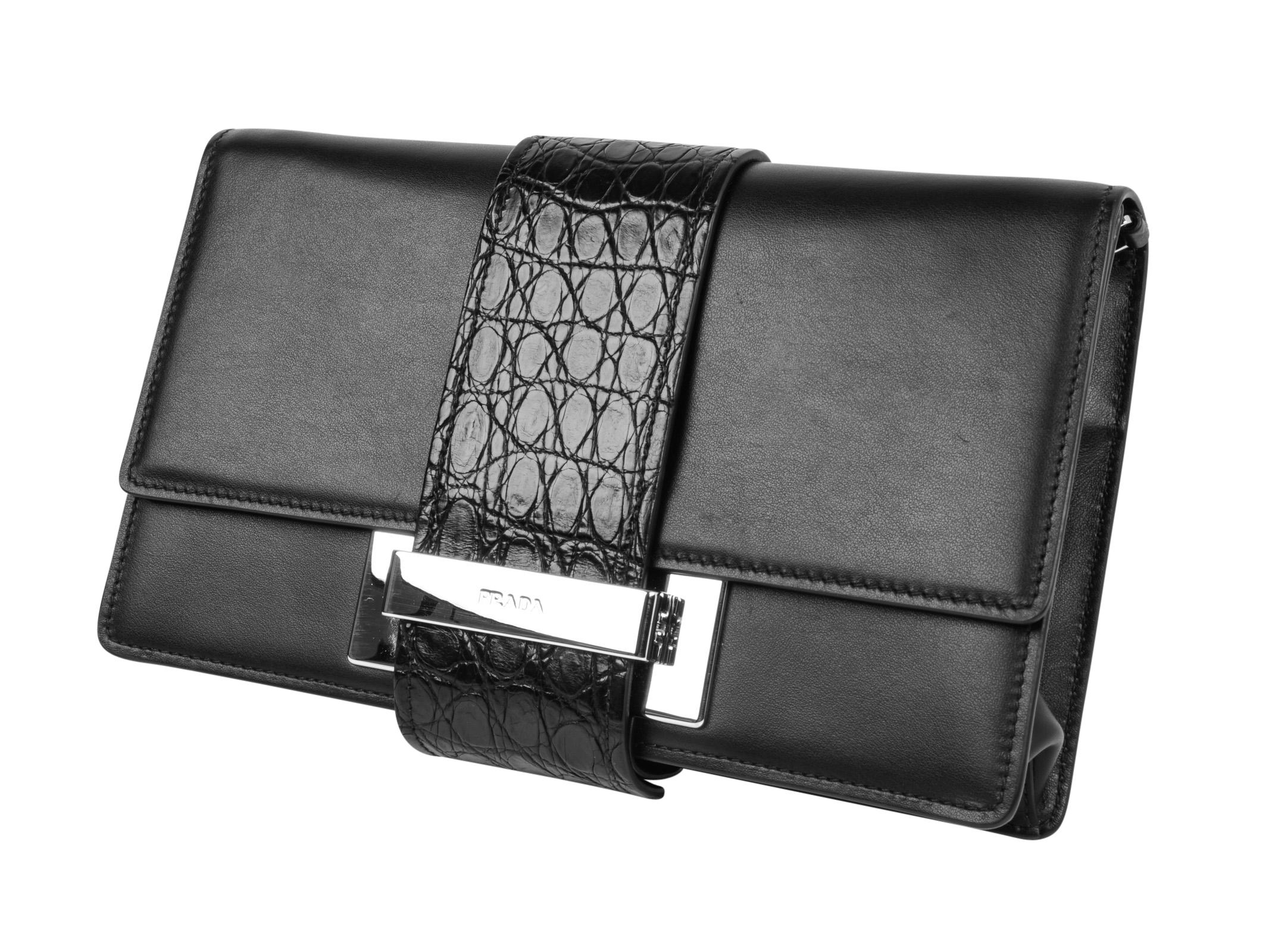 Guaranteed authentic Prada black Plex Ribbon leather clutch with front crocodile strap and silver hardware.
Elegant and versatile with leather strap to convert to shoulder bag.
Front snaps closed to secure black crocodile strap under embossed silver
