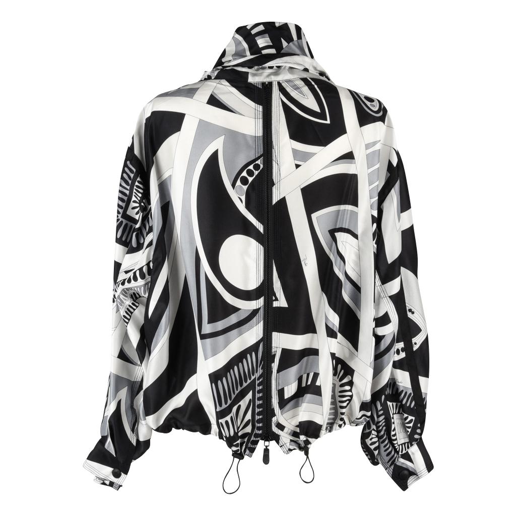 Guaranteed authentic Emilio Pucci silk windbreaker with front snap closure and rear zipper.  
Signed abstract print in black, white and gray.
Front features logo embossed snaps and zipper with 2 zippered pockets.
Dolman sleeves with logo embossed