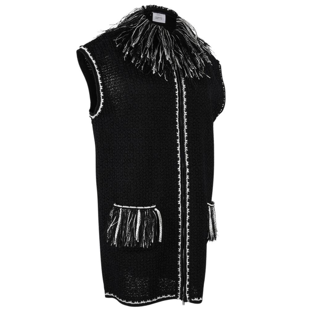 Guaranteed authentic Chanel 14S long black sleeveless slim fit vest.  
Vest has black and white fringe.
Fringe has Chanel printed on black and white thin strips.
2 front pockets with fringe.
Front zip with embossed pull.
White stitching down front