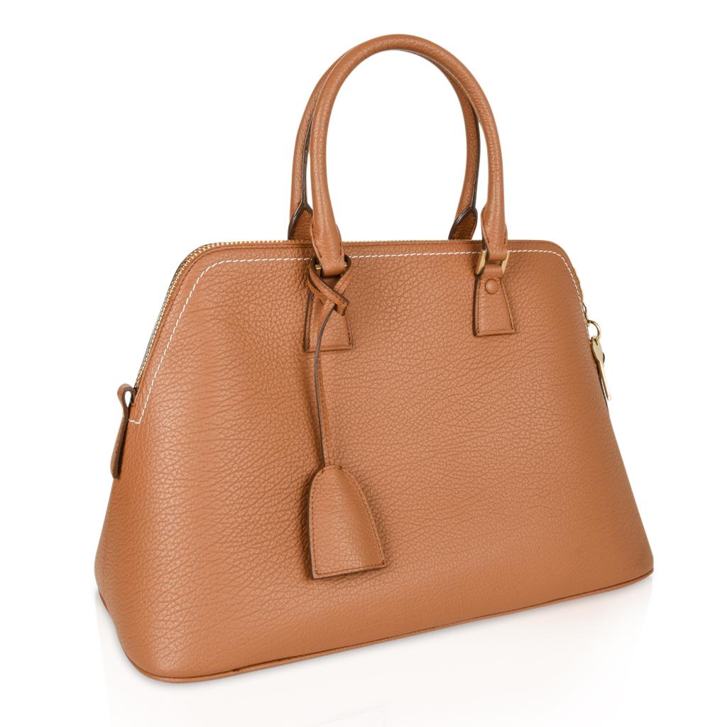Guaranteed authentic Maison Margiela 11 leather bag in classic British racing tan with white top stitch.
Bolide style bag with clochette, lock and keys.
Top zip and double handles.
5 metal feet - all in different shapes. Hardware is gold toned.
1
