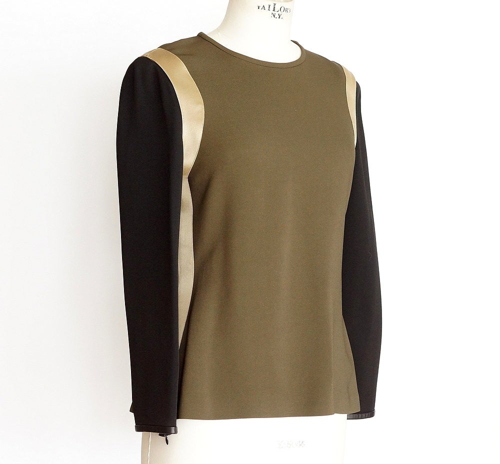 Guaranteed authentic Givenchy beautiful color blocked top in olive, black, and gold.  
Jewel neckline with gold fabric detail around sleeve opening and down each side.
Cuffs are trimmed in lambskin.
Black sleeves zip at cuff.
Hidden zipper in back.