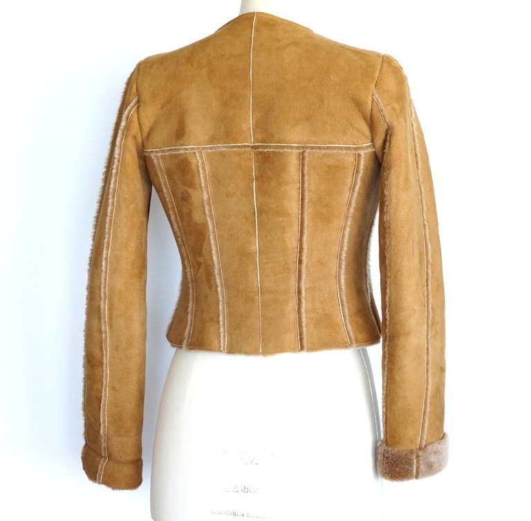 Guaranteed authentic CHANEL 99A fabulous camel shearling short jacket.
Suede is accentauted with shearling piping. 
Round neck, hidden zip front.  
Zip toggle embossed CHANEL.
Lush rich shealing inside.
Fabric is sheepskin.
Front has some