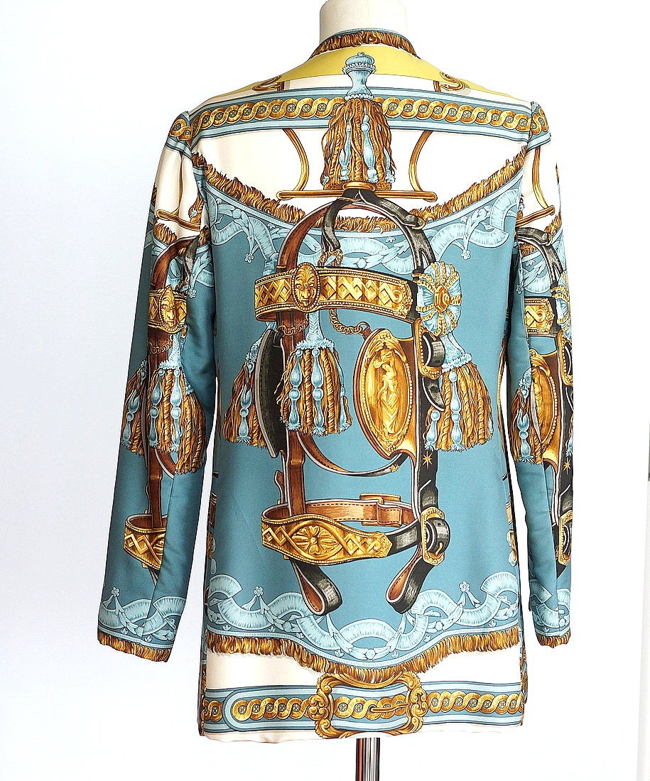 Guaranteed authentic HERMES SPORT vintage rare BRIDE DE COUR silk scarf print jacket with exquisite detailing.    
Single breast with beautifully shaped neckline.
Magnificently depicted in blues and golds on a cream background.
6 covered front