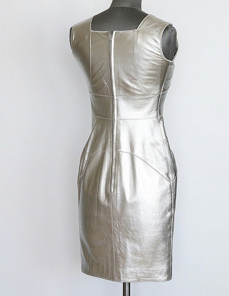 Guaranteed authentic CHANEL 99A fabulous silver lambskin leather dress.
Stunning body conscious silver V neck leather dress. 
Two angled slot pockets.
Subtle piping detail throughout to accentuate the fit.
Zip toggle embossed CHANEL.
Metal logo