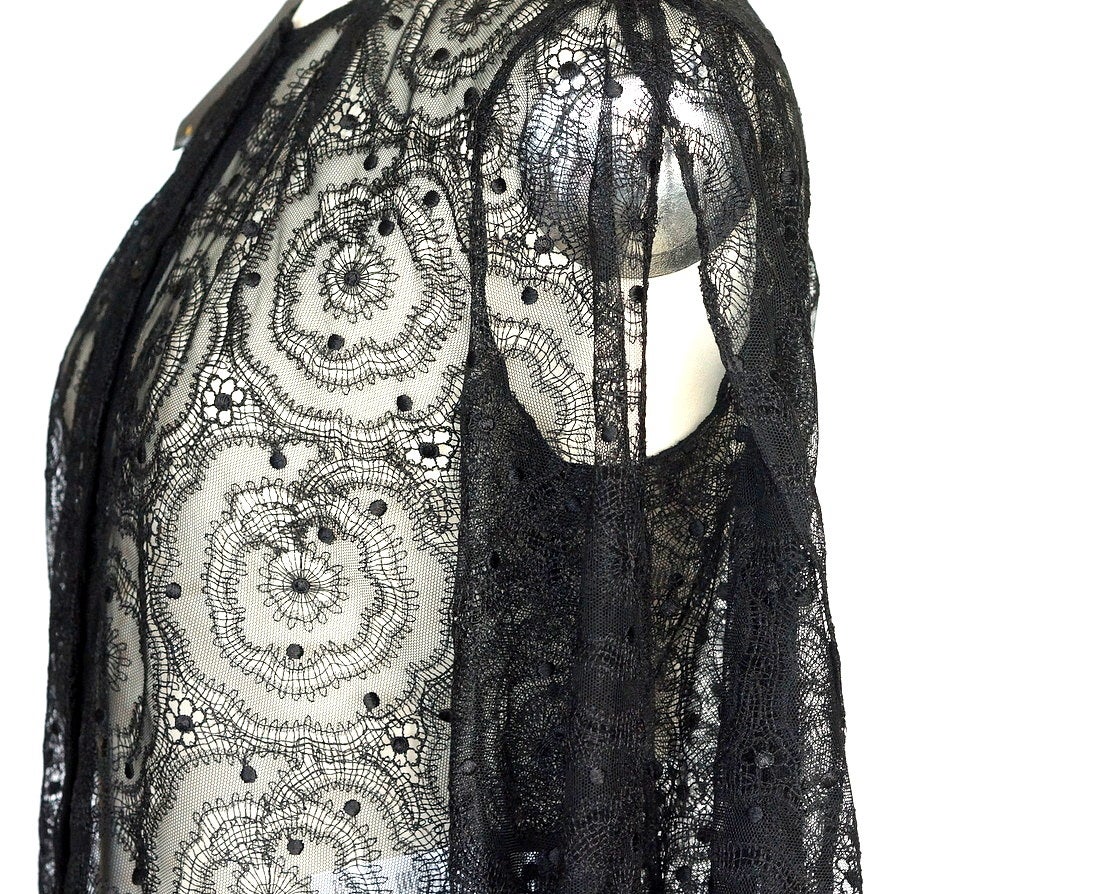 Guaranteed authentic Fendi luscious black lace blouse. 
Stunning black lace button down top with sleeves that are slit open along the outside.
Fabric wraps and twists at the wrist to create a soft puff.
Black spaghetti strap camosile goes