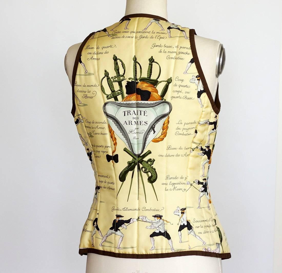 Guaranteed authentic HERMES TRAITE DES ARMES shaped scarf gently wadded print vest.
Beautiful very pale yellow background with fencing motif.
V-neck with 6 gold embossed snaps and brown piping all around.
Gentle wadding.
Beautiful brown silk