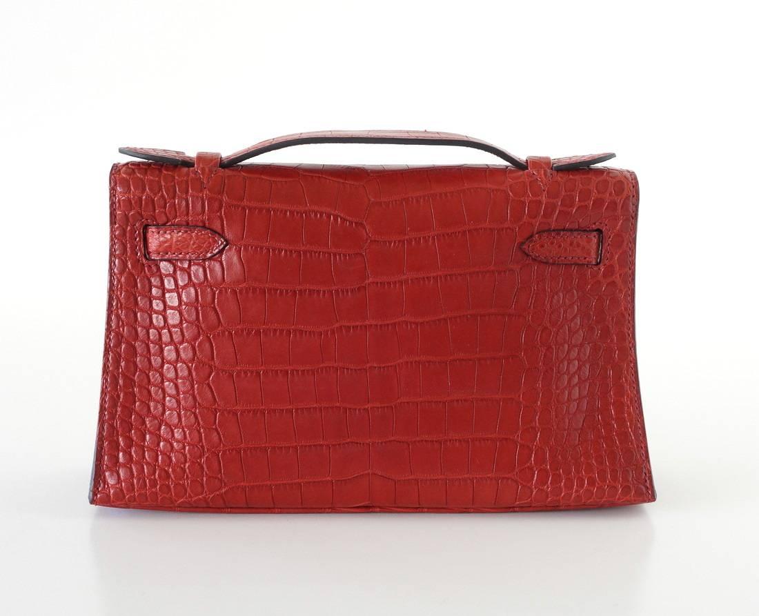 Guaranteed authentic Hermes Kelly Pochette in exquisite rich jewel toned Rouge H with gold hardware.
Exotic with matte alligator. 
This treasure can be carried day or night.
Small interior compartment.
Comes with sleeper and signature HERMES box.