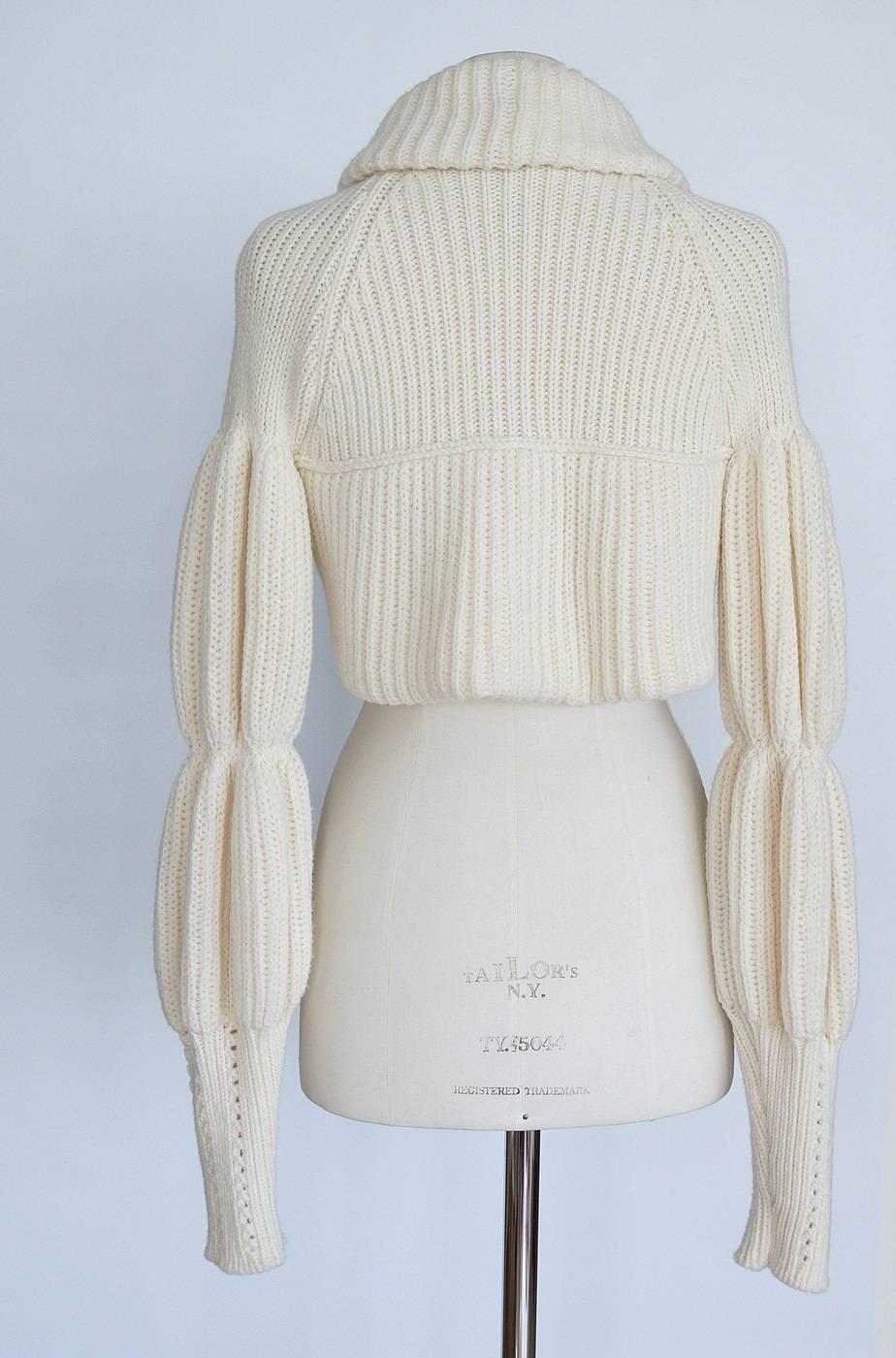 
Guaranteed authentic VALENTINO unique cardigan shrug. 
Thick ribbed knit in off white cropped cardigan shrug.
Rolled shawl collar that runs into bottom around the back.
Cut up in center of front with a single snap at front center.
Long sleeves