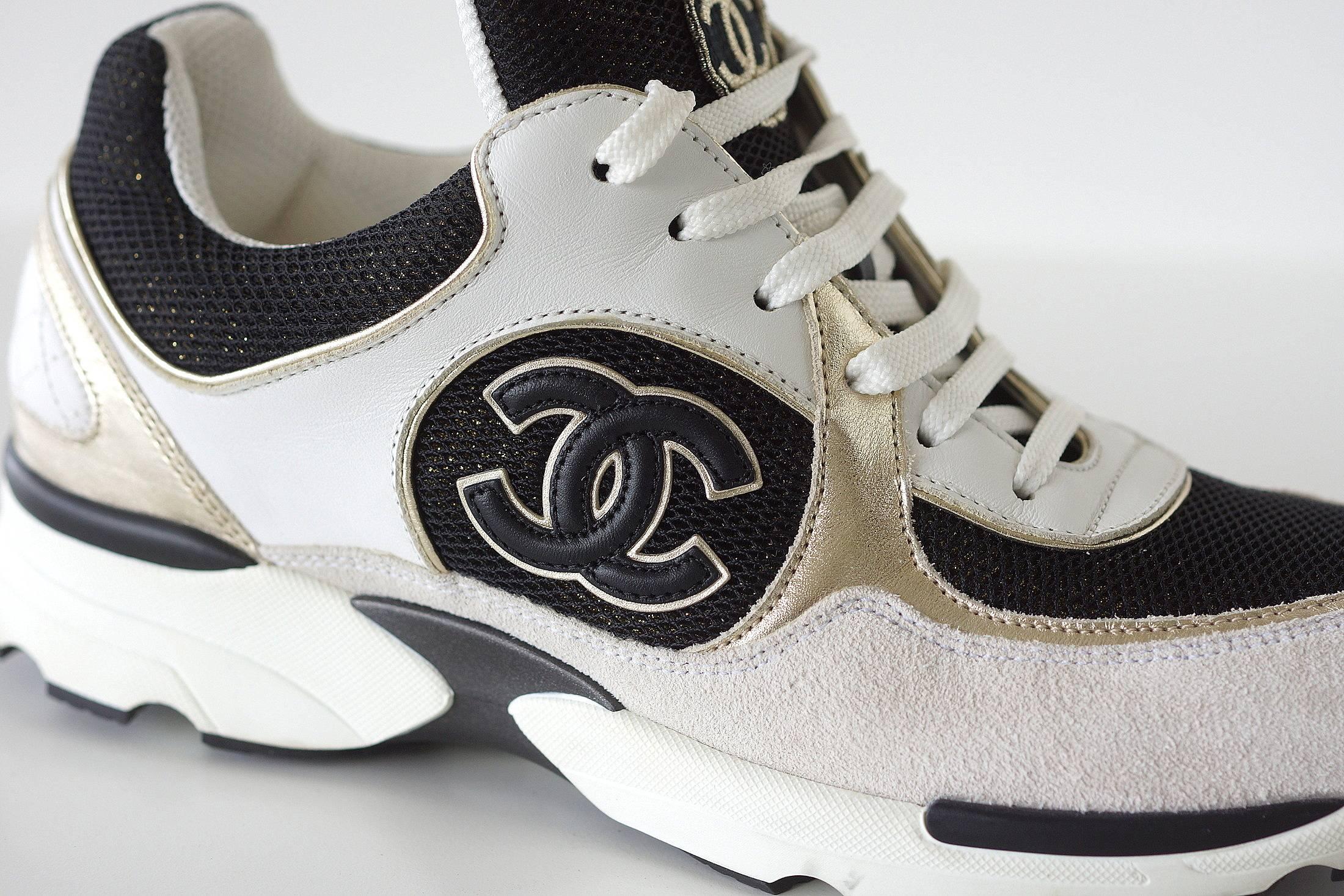 Guaranteed authentic CHANEL leather tennis sneaker in white, gold and black glitter effect textile. 
Black CC rimmed in gold on side of shoe.
Tongue has black CC rimmed in gold.
Black has gold metallic shimmer.
Signature white quilting at rear