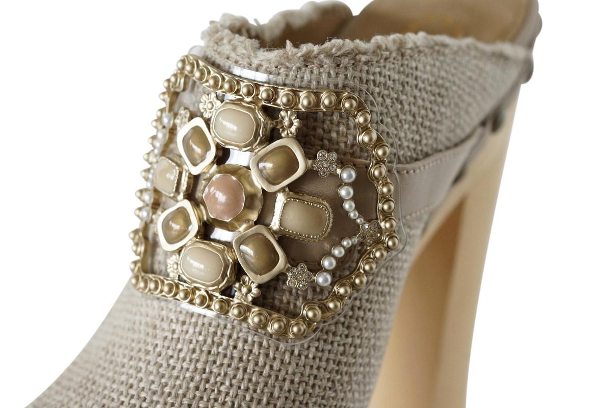 Mightychic offers limited edition Chanel clog shoes.
Beige linen with iconic cap toe.
Jewel accent is detailed with cabochons in muted shades with matte gold.
Tiny diamantes accentuates the setting.
All nails are antiqued finished.
One on the