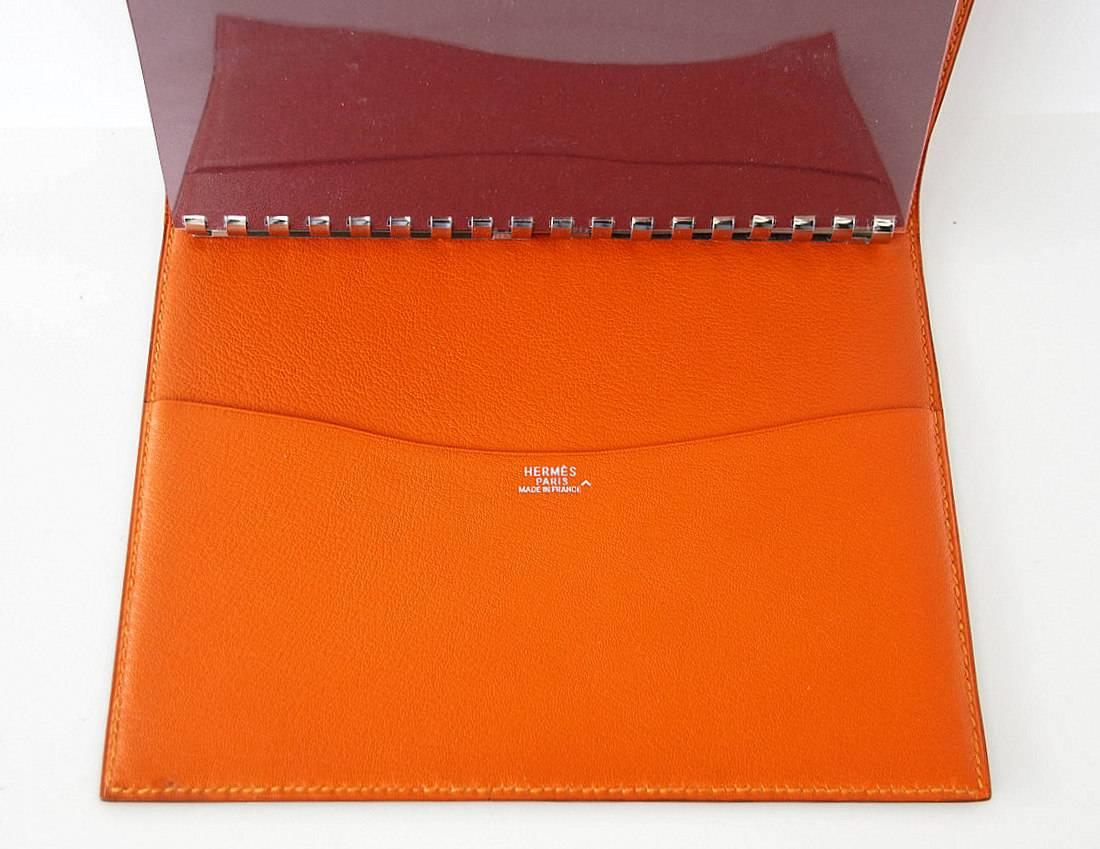 Guaranteed authentic Hermes Globetrotter Agenda beautiful Porosus Crocodile featured in Orange Feu.
Inside lined in Chevre leather with rear slot pocket.
Stamped HERMES Paris Made in France
Metal ring binder holds gold edged unlined paper.
Booklet