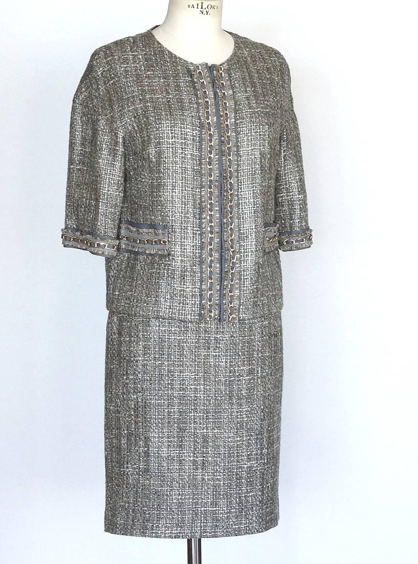 Guaranteed authentic St. John Couture beautiful taupe and gray tweed suit.
Tweed has silver threads running throughout.
Jewel neckline and 3/4 length sleeves.
Drop sleeve shoulders.
Jacket has gold chain with gray grosgrain ribbon down the front,