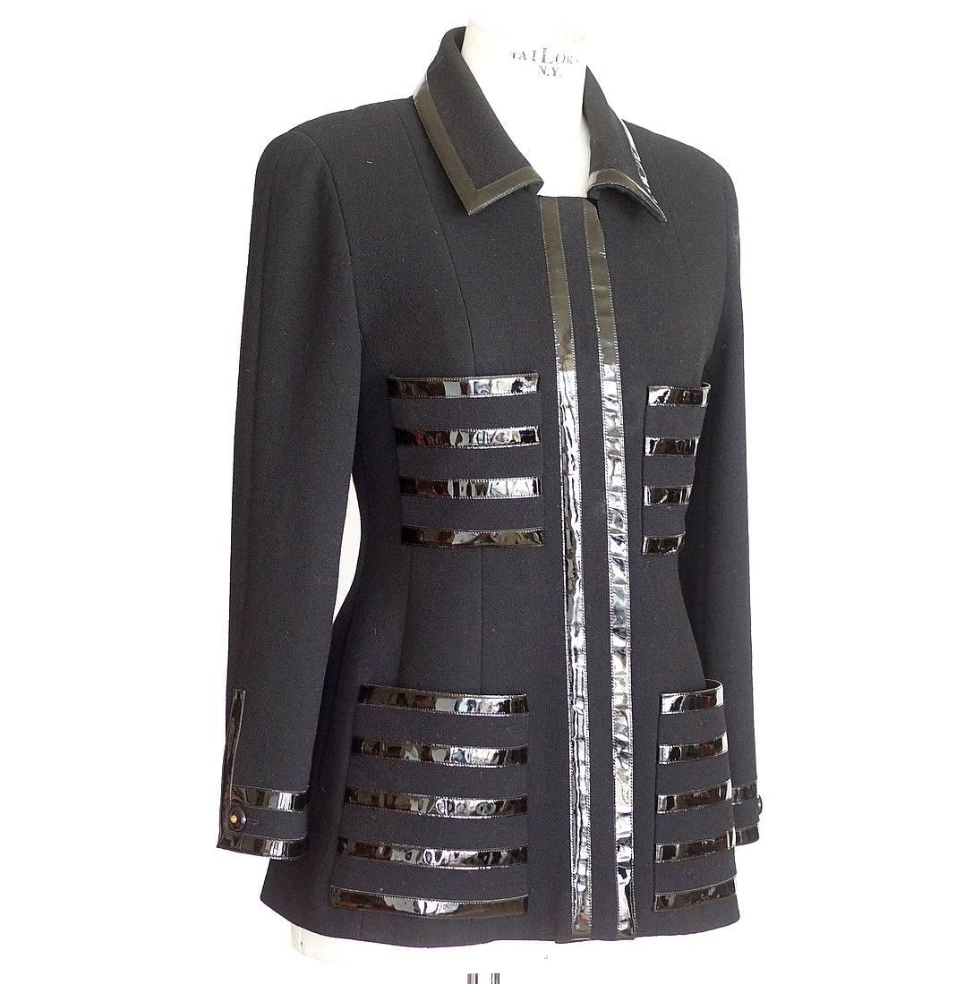 Guaranteed authentic Chanel jet black jacket with patent leather accent trim.  
Single breast jacket with leather trim throughout.
Hidden placket in front with 6 buttons.
4 Pockets.
Each cuff has 1 logo embossed button.
Some of the patent has some
