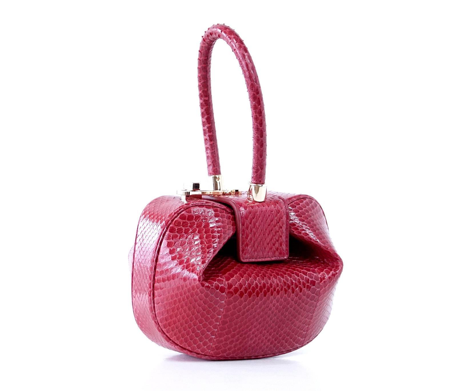 Guaranteed authentic Limited Edition Nina divine small evening bag is sultry red snakeskin.
Rose gold toned hardware with turn-lock top.
Iconic shape and rolled handle.
Interior is lined in matching leather with 2 card slots. 
NEW or NEVER WORN.