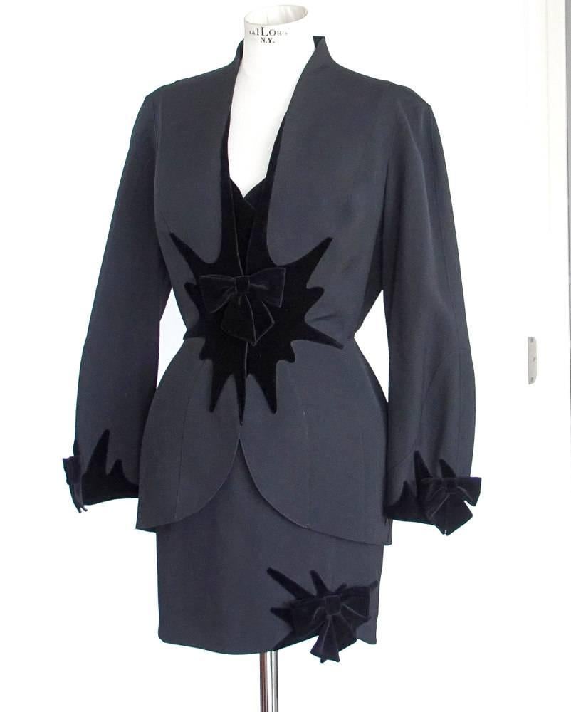 Guaranteed authentic THIERRY MUGLER vintage black suit accented with velvet starbrusts and bows.
Single breast jacket with starburst black velvet detail in front.
Black velvet bow at center with snap closures.
Mini burst and bow on each