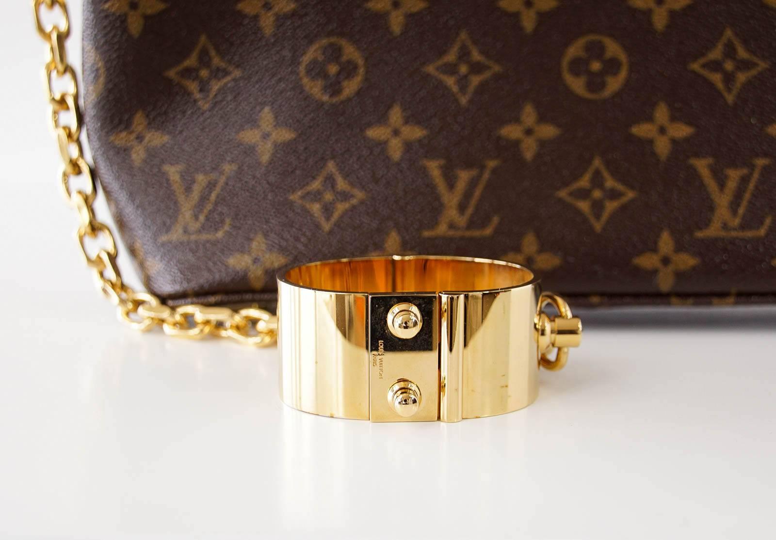 Guaranteed authentic Limited Edition Louis Vuitton Runway 2011 - 12 Fetish Collection monogram Autumn 2011 - 12 wristlet clutch.
Monogram has sheen finish.
Embossed gold bracelet/cuff is attached to a gold link chain which attaches to bag.
Top zip