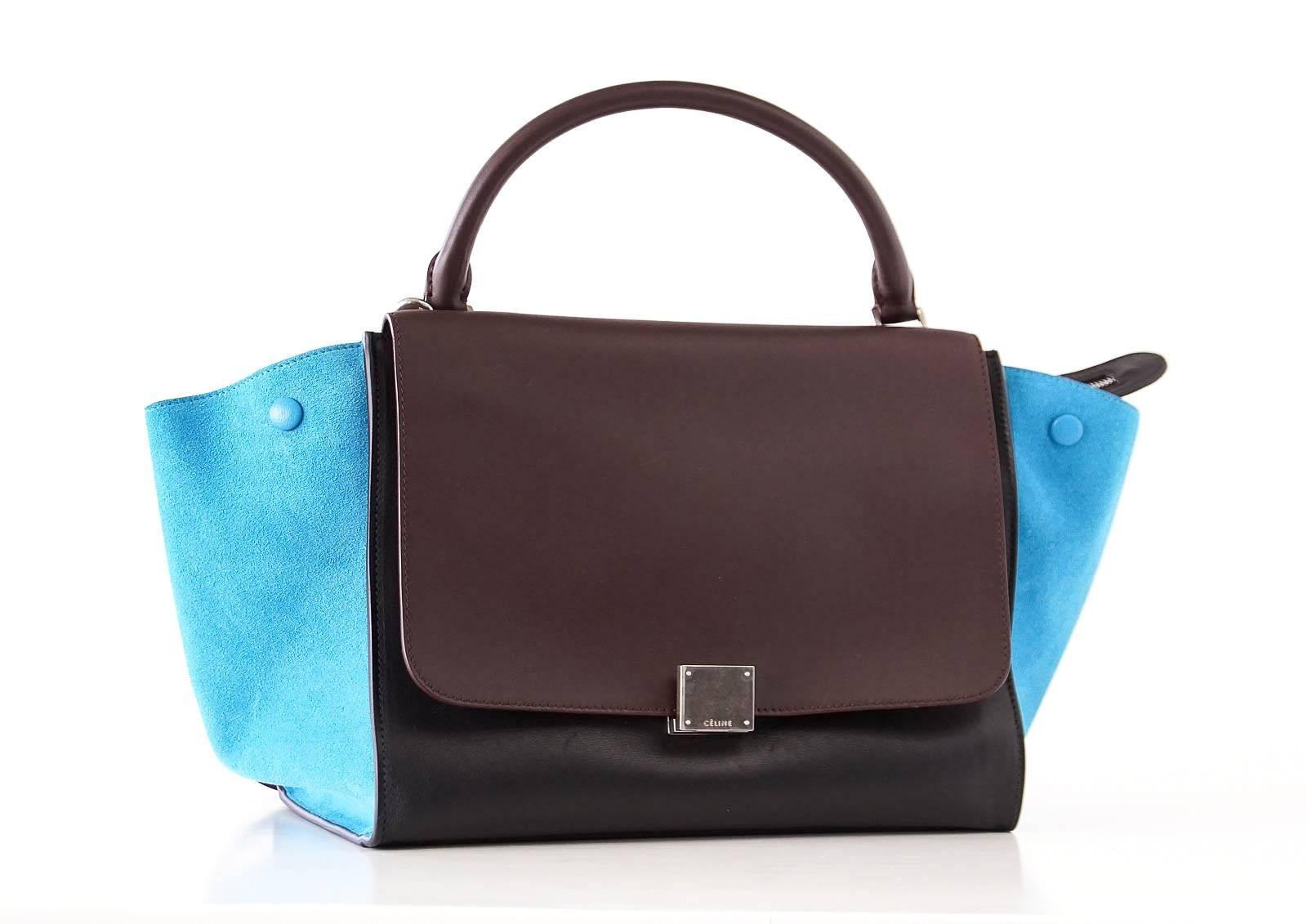 Guaranteed authentic medium Celine Trapeze beautiful tote bag.
Chic combination of black and brown leather with blue suede side panels.
Front flap with logo hardware opens to reveal zip top.
Interior has 2 slot pockets and logo plaque.
Rear exterior