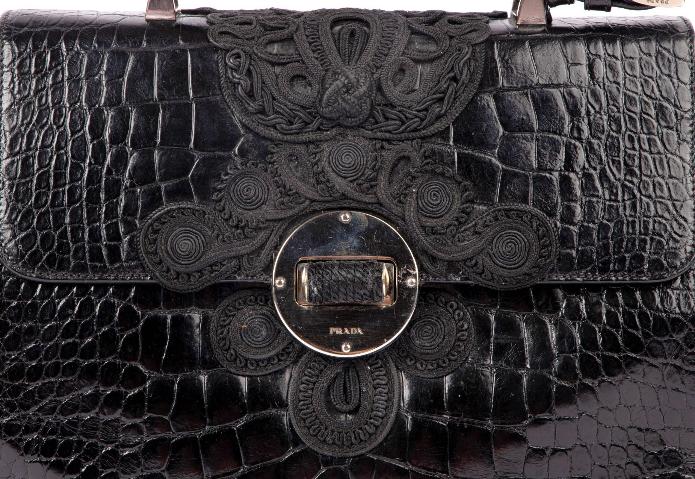 Guaranteed authentic vintage VERY rare Prada Black Alligator with beautifully detailed Passementerie in black.
Flat top handle is accented with silver hardware. 
Silver hardware at turnkey to open flap. 
Interior is burgundy lambskin leather. 
Has