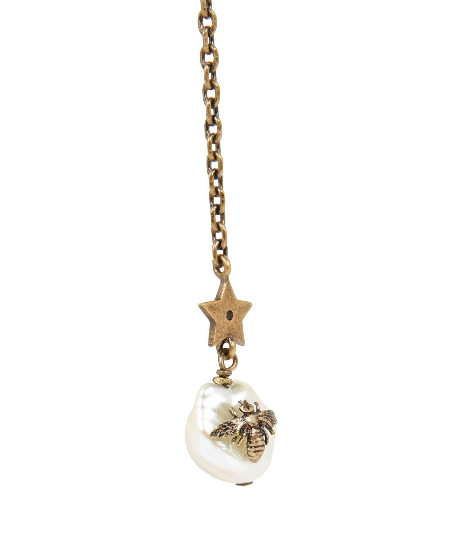 Mightychic offers a Christian Dior antiqued gold toned lariat Y necklace.
Fresh water pearls interspersed with antiqued gold stars and CD logo.
The last pearl on the lariat has an antiqued gold bee on it.  
Logo embossed metal CD charm at closure