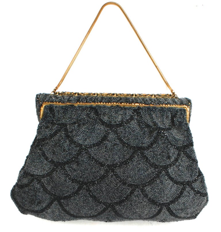 Black micro beaded evening bag in a scalloped design and a gold-tone floral incised hinged frame with a black vine enameled band.  Purse has a 11'' gold-tone snake chain handle and a hinged and beaded tab closure. It is lined in grey satin with one