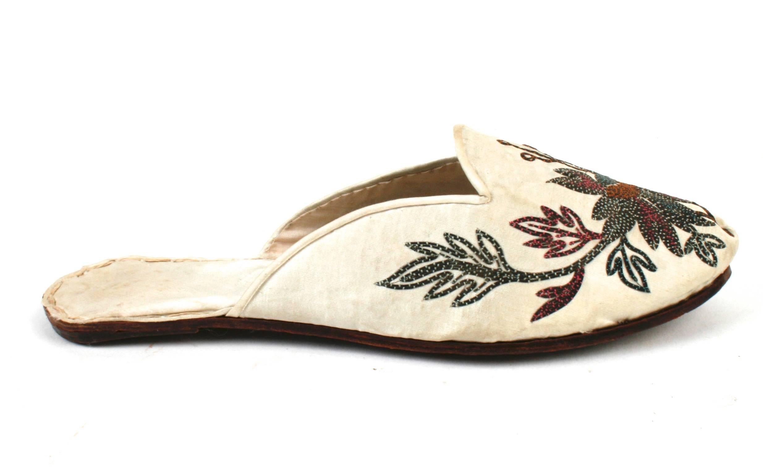 Handmade Indian ivory silk floral embroidered flat-heeled mules with leather soles. Mules are trimmed in a dark green and brick colored embroidery with self covered piping and lined in a matching ivory silk brocade. The leather soles have brass nail