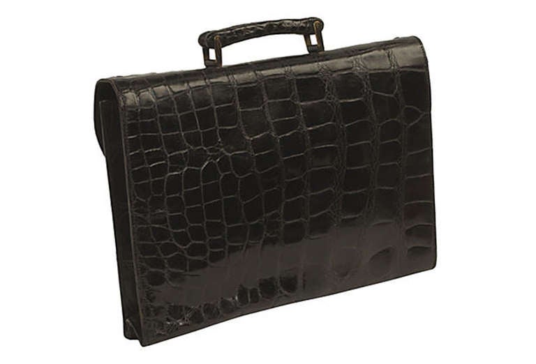 Loewe black fine belly skin alligator single gusset briefcase. Alligator handle with brass hardware, original key and brass latch. Flap opens to a smaller flapped pocket and an interior with three compartments, one with a zippered closure.
N.P.