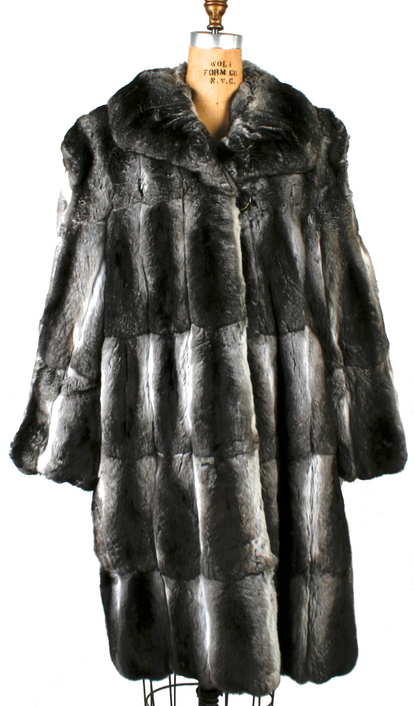 Revillon grey Chinchilla fur coat from Saks Fifth Avenue with shawl collar and a single button overlap closure. The fur coat has padded shoulders and is fully lined in black. It has one outside left-hand pocket and an interior right-hand pocket. The