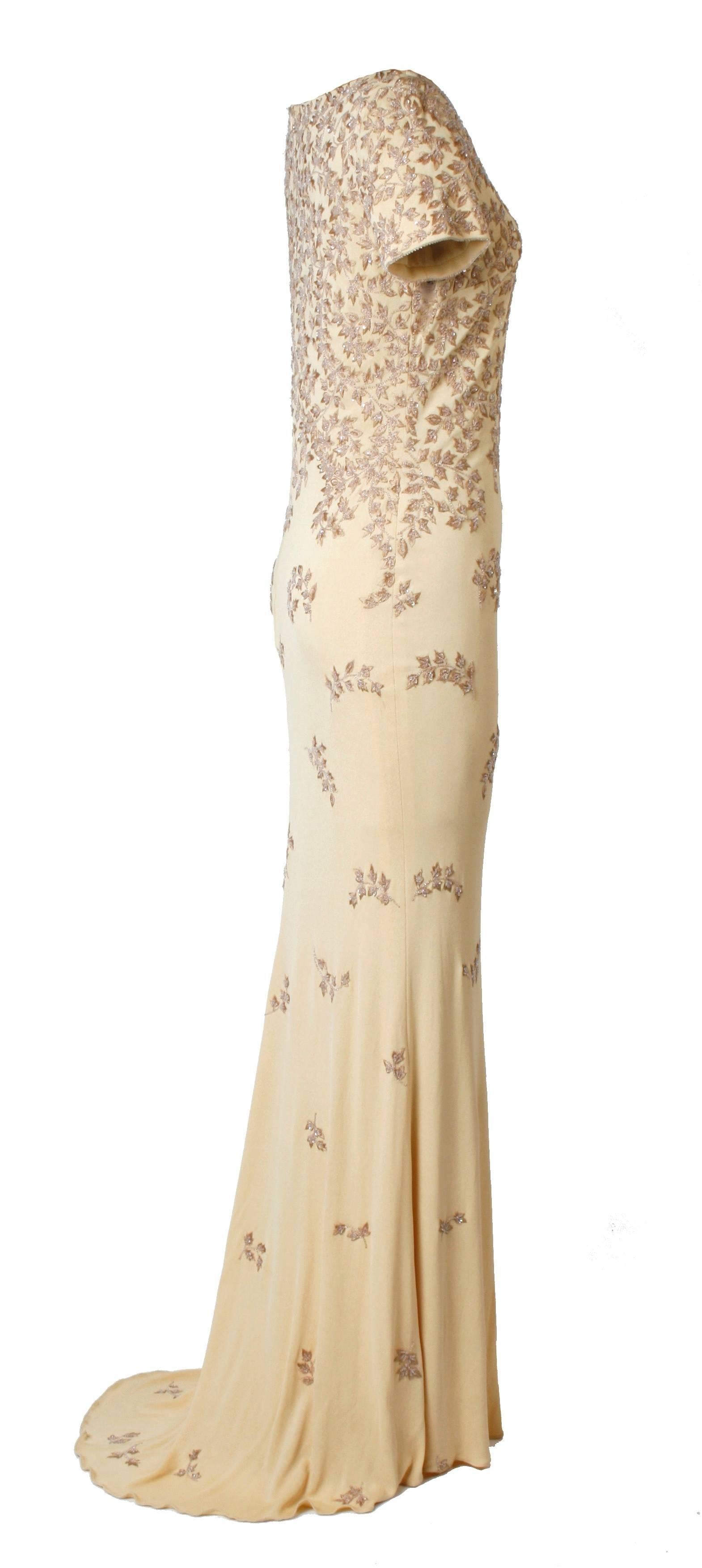 A beautiful Naeem Khan champagne colored beaded and embroidered crepe evening gown with a fish tail. The gown is beaded with a graceful vine motif. It is a size 8 and is lined. It's label reads ''Naeem Khan'' and ''Rayon 8''. It also has it's