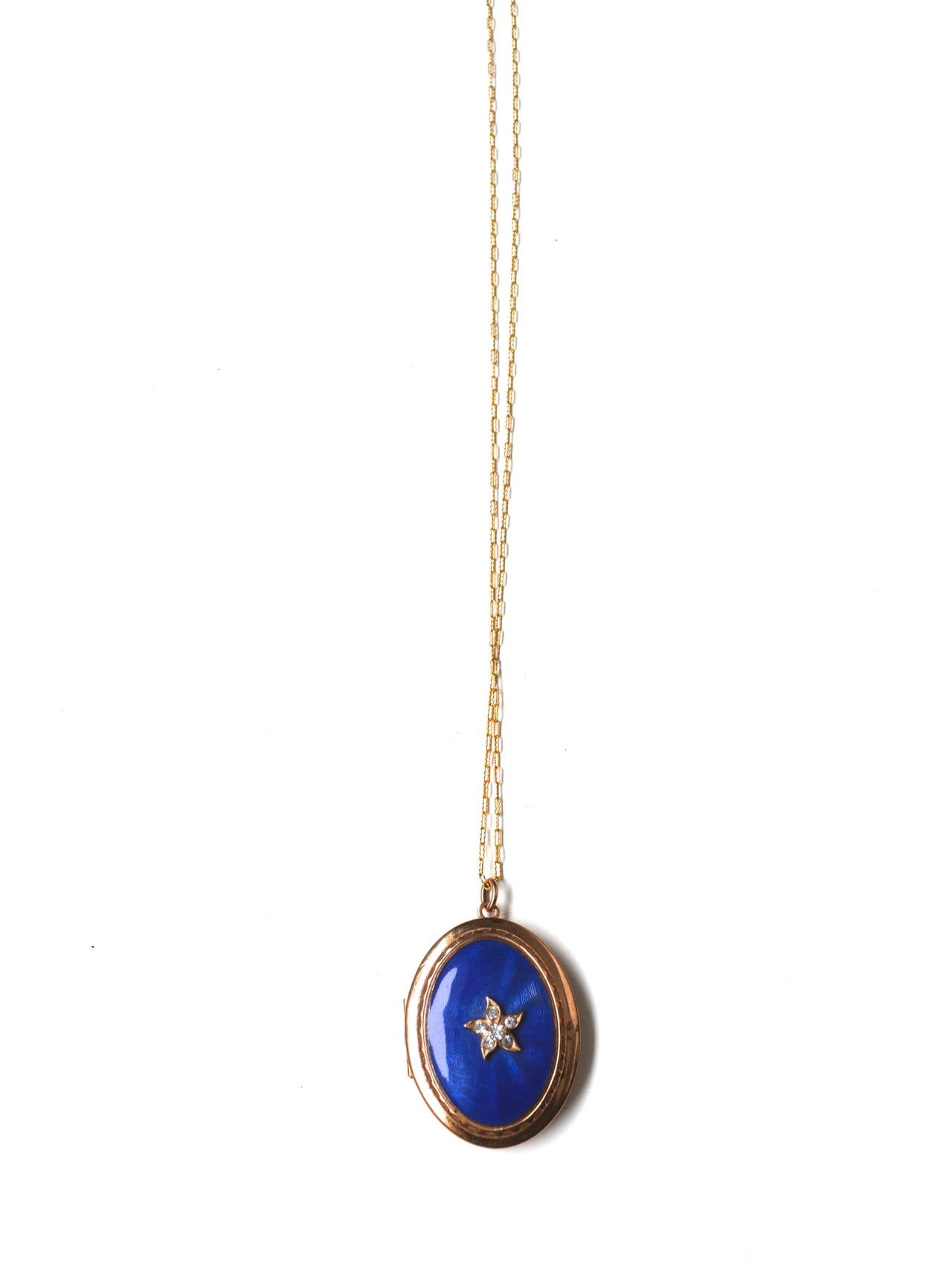 Vibrant blue guilloche enamel locket with paste stones and a larger scale. The piece appears well made with nice golden patina to the brass locket. The contemporary gold filled chain is included and matches the piece's style well. Pendant is 1.5