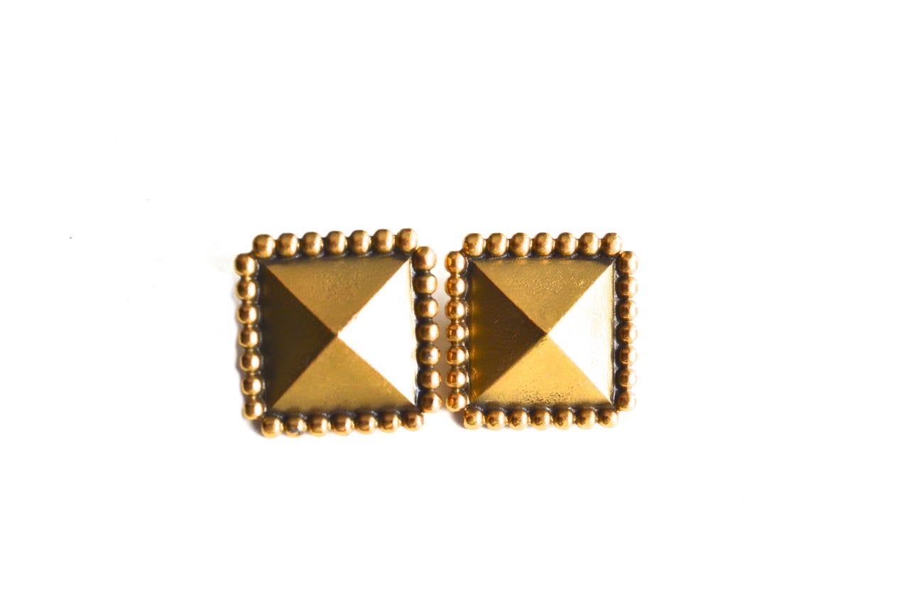 Signed YSL designer stud clip earrings. Fab modern aesthetic and great scale. Antiqued golden finish with soft push lever clip, which is nice and secure. Size 1″ long.  Condition is excellent. Possible pair to the YSL armor cuff set, in the shop now