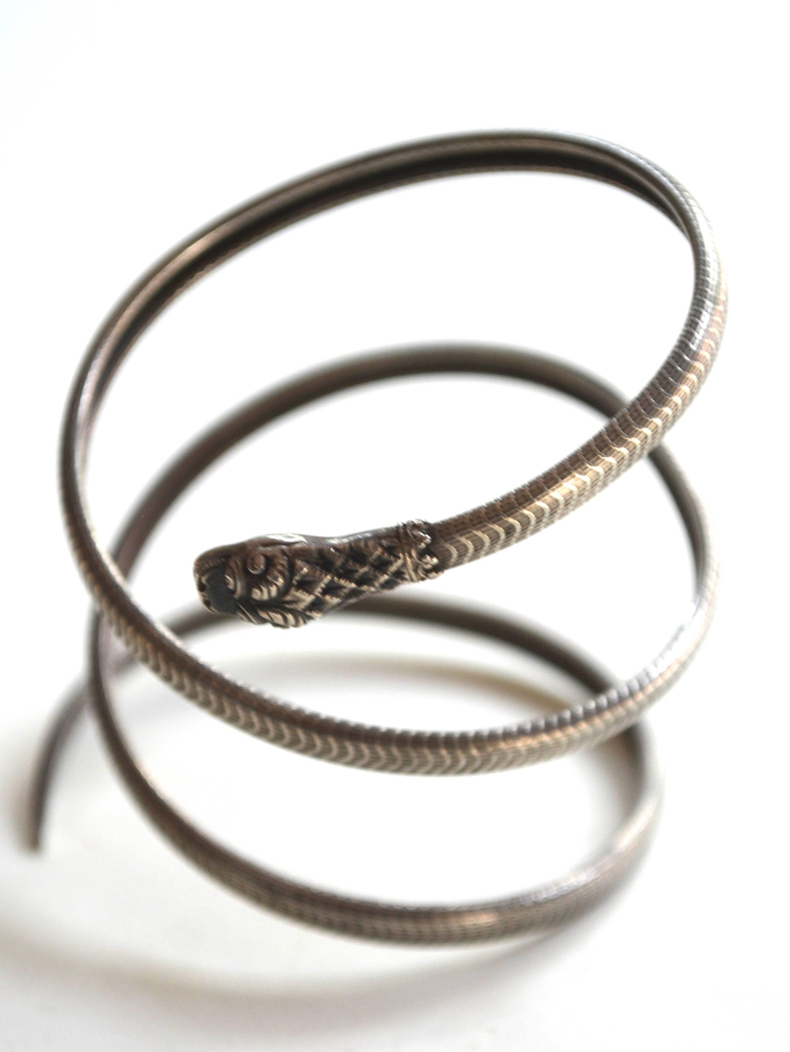 Edwardian silver textured metal, almost gothic snake bracelet. It wraps on and has a thinner more petite construction that works as a whole which has impact. The head appear to possibly be a silver, maybe 800 and the body could be brass with a