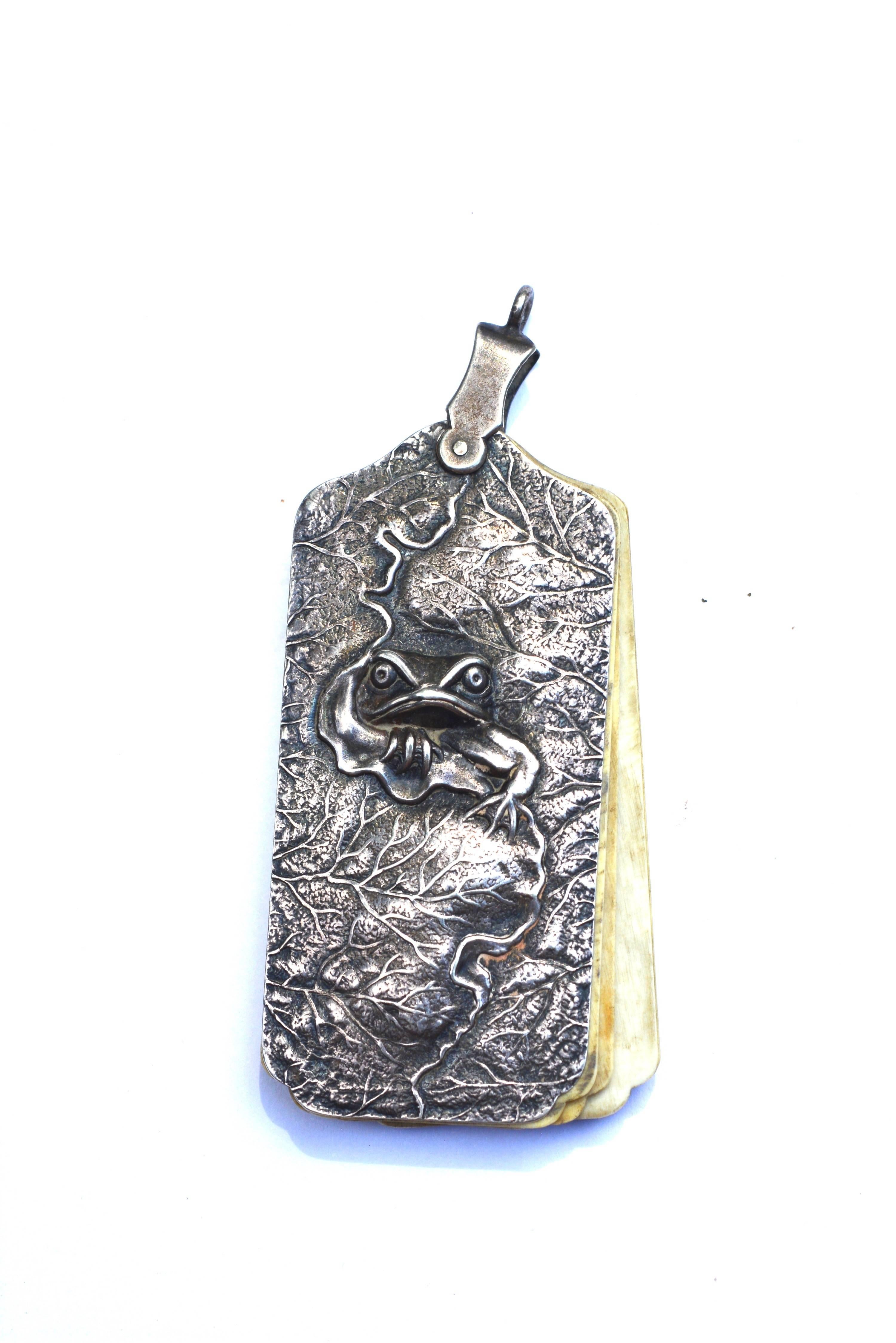Sterling Silver Chatelaine notepad with a whimsical frog and lily pad design. Can be mounted on a chain as shown here. Celluloid pages marked with the days of the week. Chain not included.  Late 1800s-Early 1900s. Marked sterling with an S inside