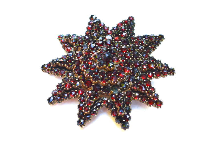 Late 1800s star or burst style unsigned 10k gold and garnet brooch.  The design makes this piece a lovely example of bohemian jewelry.