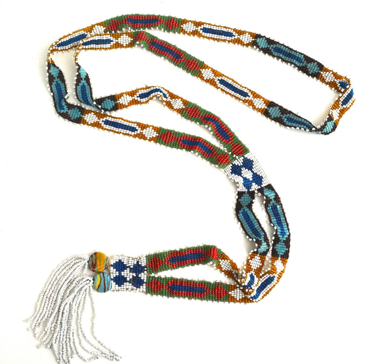 Vintage loom beaded glass necklace with white fringe, unsigned. The piece celebrates color and is possibly of Native American origin. Style and materials suggests a 1920s date. Trade beads at the bottom display color and some age. Strong and