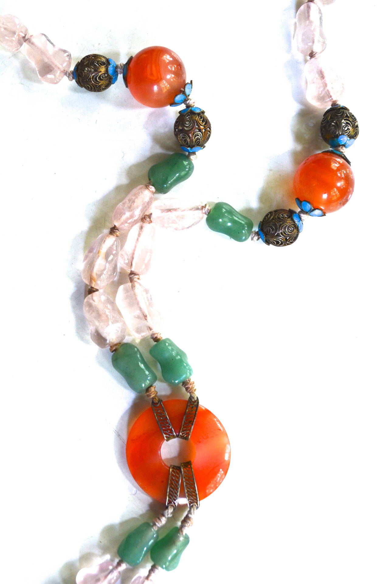 Chinese silver and gemstone knotted necklace. Featuring carnelian, blue enamel, jade and pink quartz. Pendant design drops 5.5" from 30 gemstone collar. Width varies with the center carnelian piece being 1" wide.