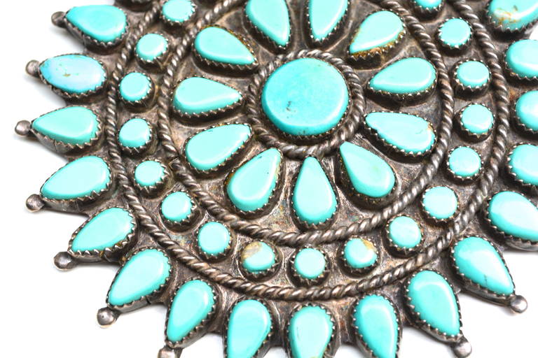 Older coin silver Zuni unmarked natural turquoise brooch.   3″ diameter.  The color is simply stunning. The piece has nice design elements
and construction.