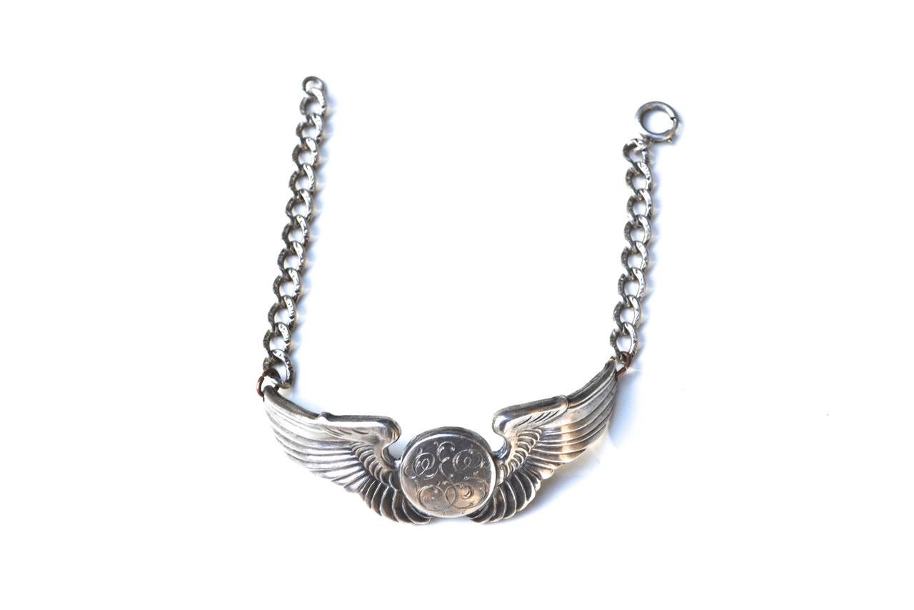 Vintage winged initial sterling bracelet with intricate chain.  The piece has elaborate scrolled letters which are almost abstract and may read JS, SS, or GS.  They have the appearance of vines.  The wings and center pendant are thicker in weight