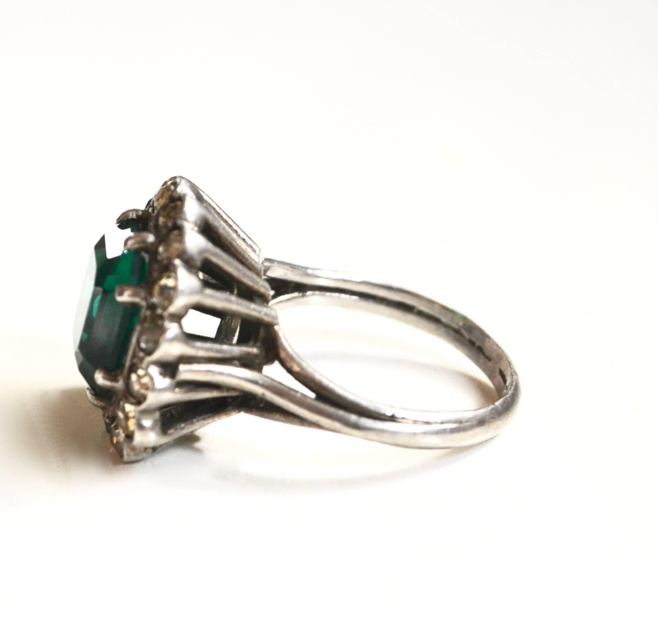 Vintage glass emerald-green and paste stone cocktail ring. French hallmark of a crab and illegible second symbol on the outside bottom area. Sterling tested. Face measures approximately 1.3"L. Mild wear and tarnish.
