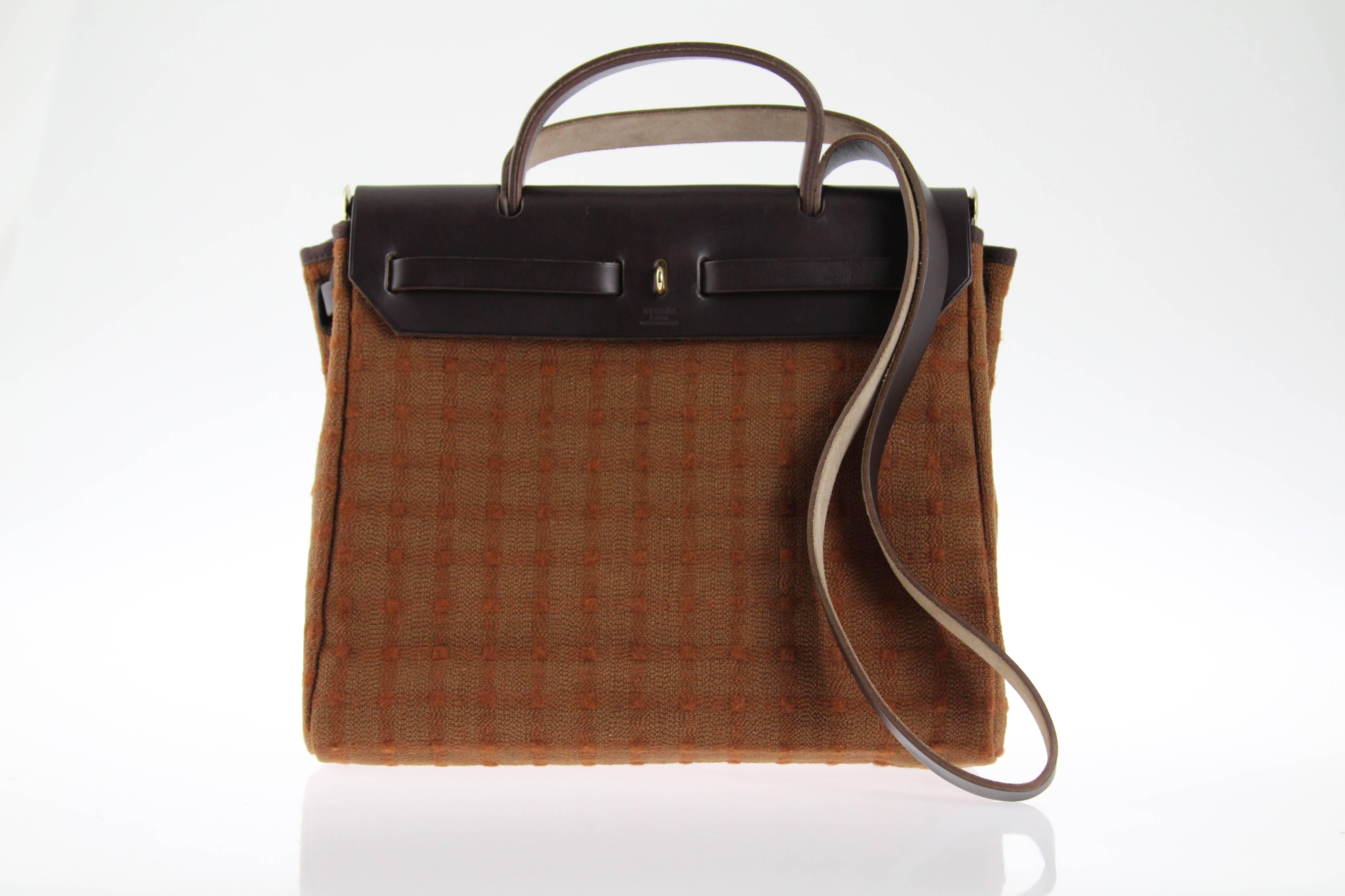 Brown calf leather and camel fabric Hermès HerBag from 2004, as blind stamped square. Stylish as a Kelly, but more casual.
As the pictures show, the bordeaux interior can be removed.This amazing tote bag comes with its shoulderstrap.
Meausurements:
