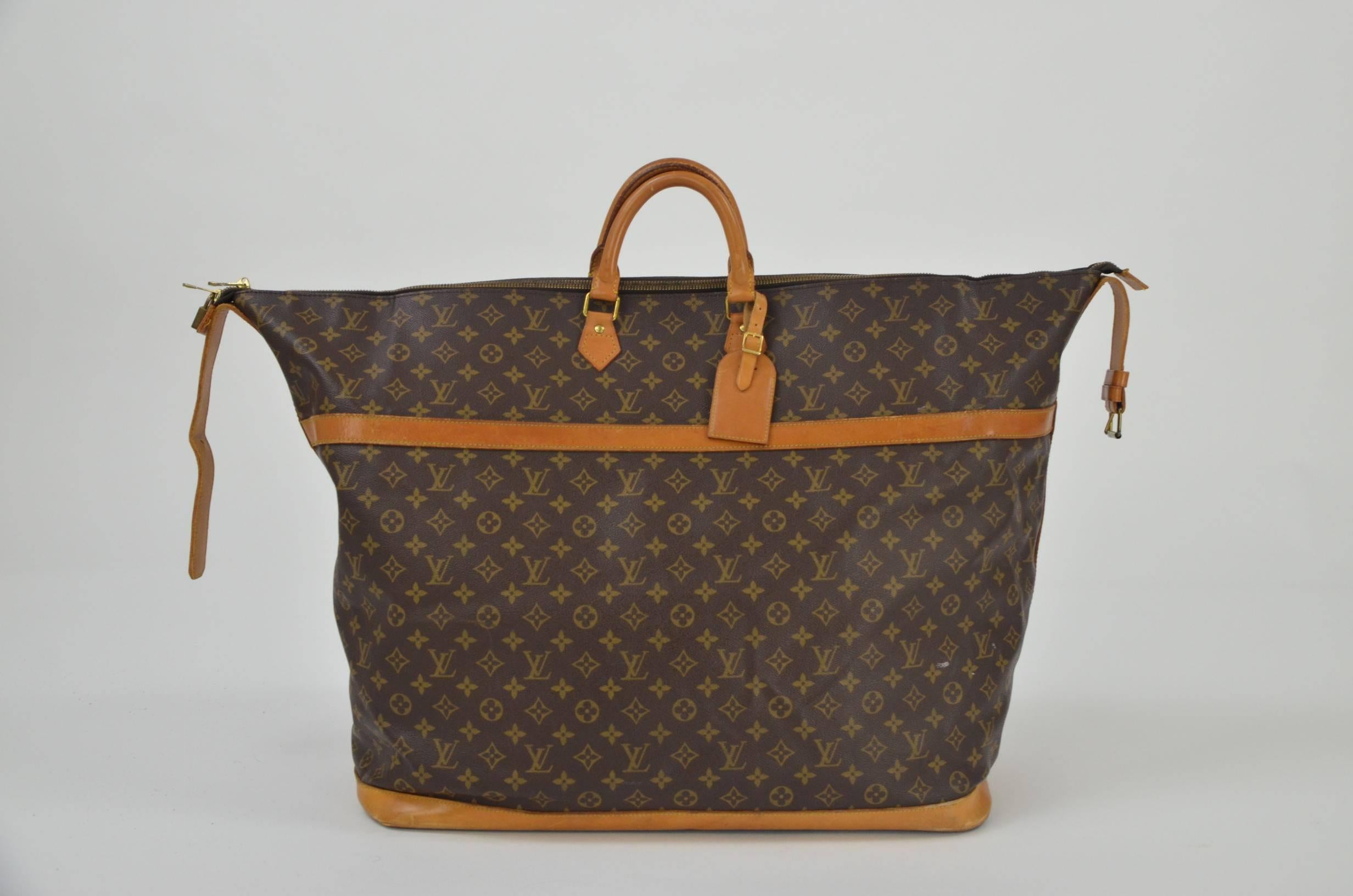Louis Vuitton monogram holdall, in leather and canvas featuring a top zipper and two handles. It can be carried with the two top handles or with a shoulderstrap. It comes with the padlock but the key is missing. This item is not in production