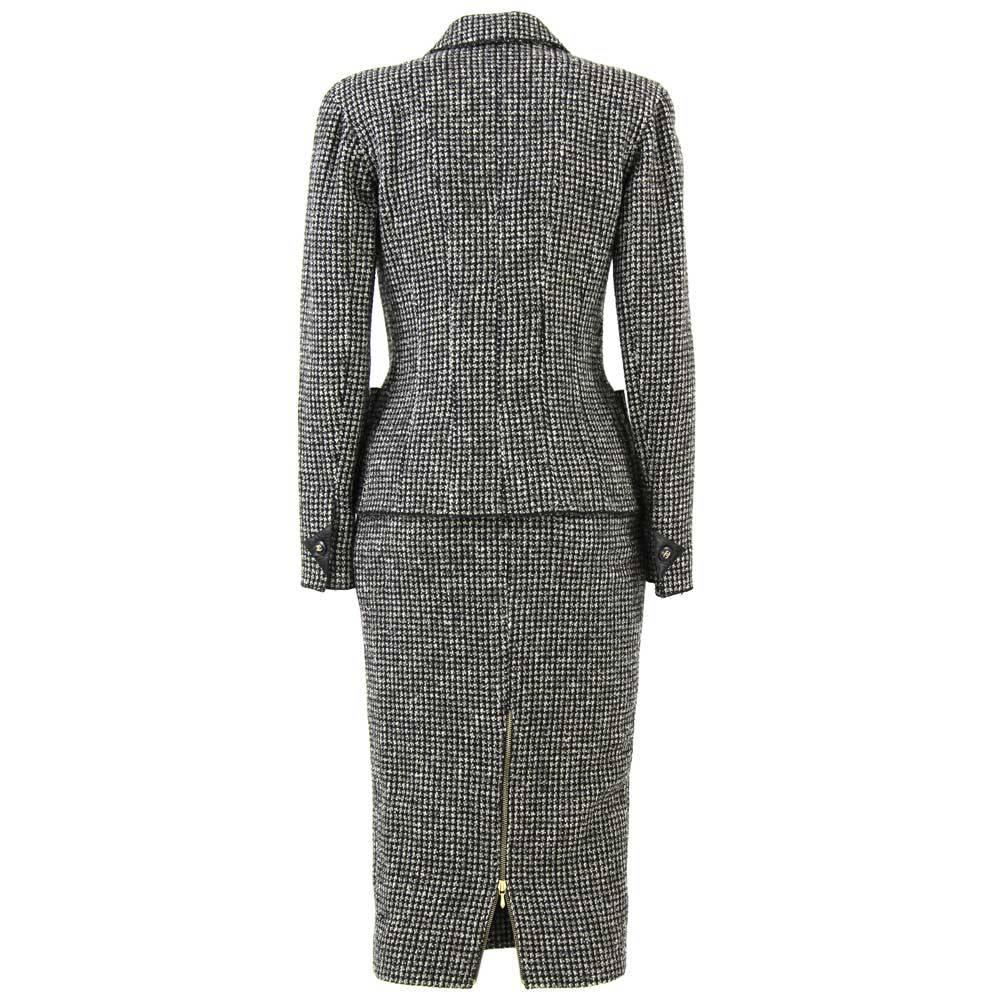 Stunning Chanel houndstooth wool suit with black leather details and buttons with brand logo. This luxury piece features 4 pockets with press-stud closure.
Dates back to the Eighties. It's in very good conditions.

Measurements:
Height of the