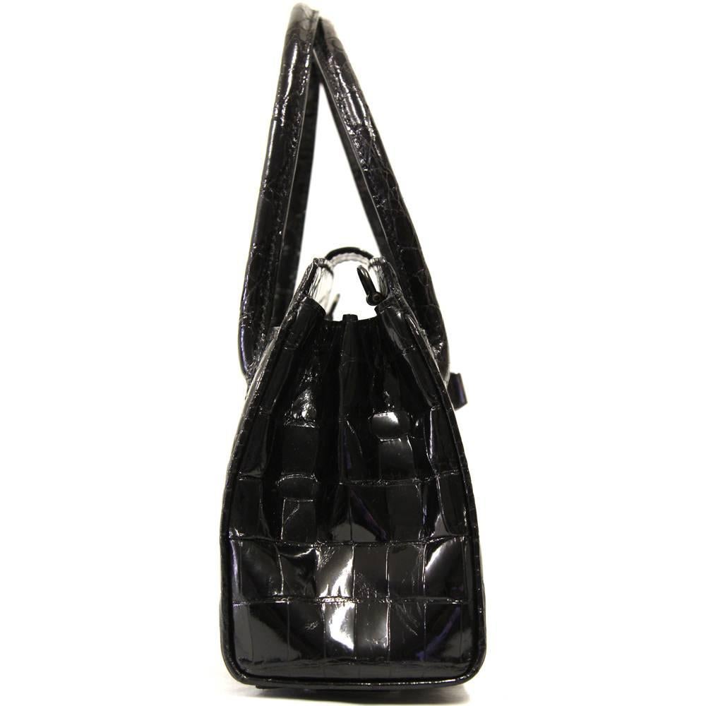 Luxurious Dotti purse in black crocodile leather. This little piece of art has a turnlock and very fine handles but also features a cotton strap. The interior is beautifully organized and includes two zip pockets and two standard pockets with a
