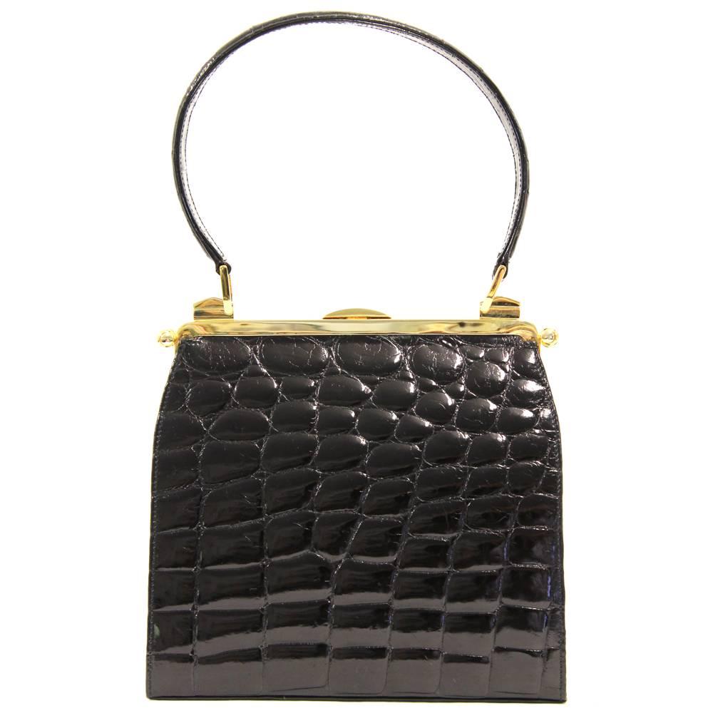 This Dotti bag is such a stunning luxury piece. Made of lavish crocodile leather, it has golden hardware and closes with a safe lock. The interiors are simply adorable with a pale green lining and two pockets. Also features a removable leather