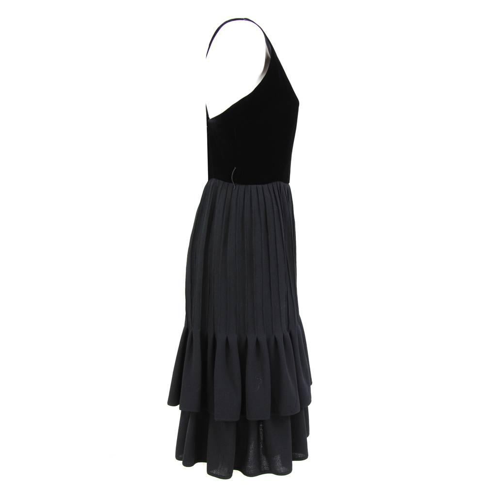 Smart Valentino black evening dress with a velvet bodice and cross back straps. Wool pleated skirt with two rows of frills. Lateral zip.
Height: 111 cm
Bust: 43 cm
Waist: 35 cm