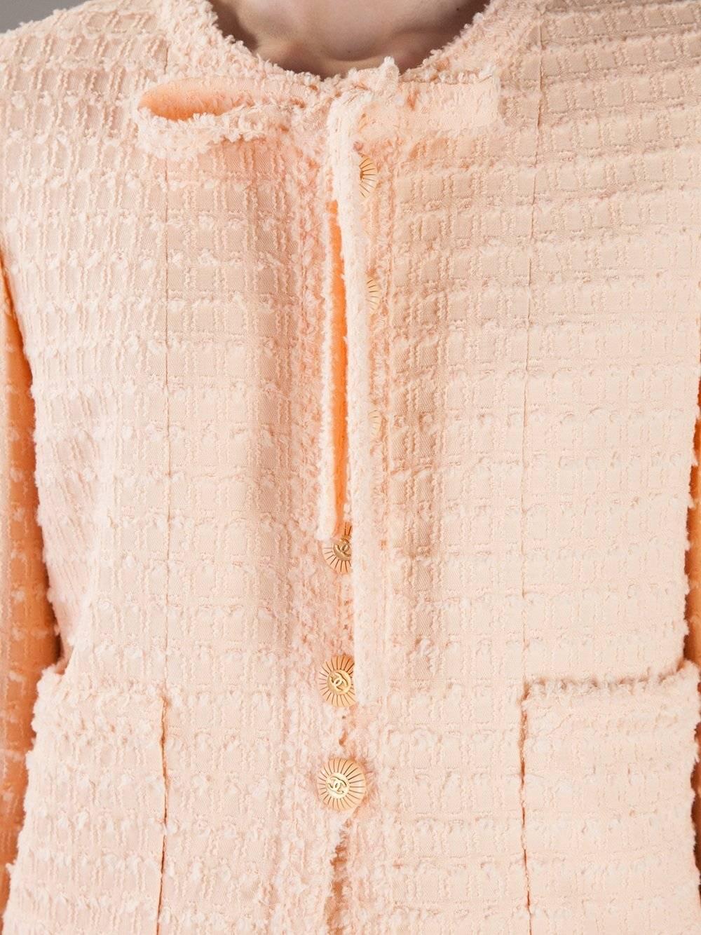 Beautiful Chanel jacket in a salmon pink bouclé wool. Round-necked with a bow, it features two frontal pockets, frontal closure with logoed buttons and buttoned cuffs. The item is vintage, it was produced in the 80s and is in very good conditions